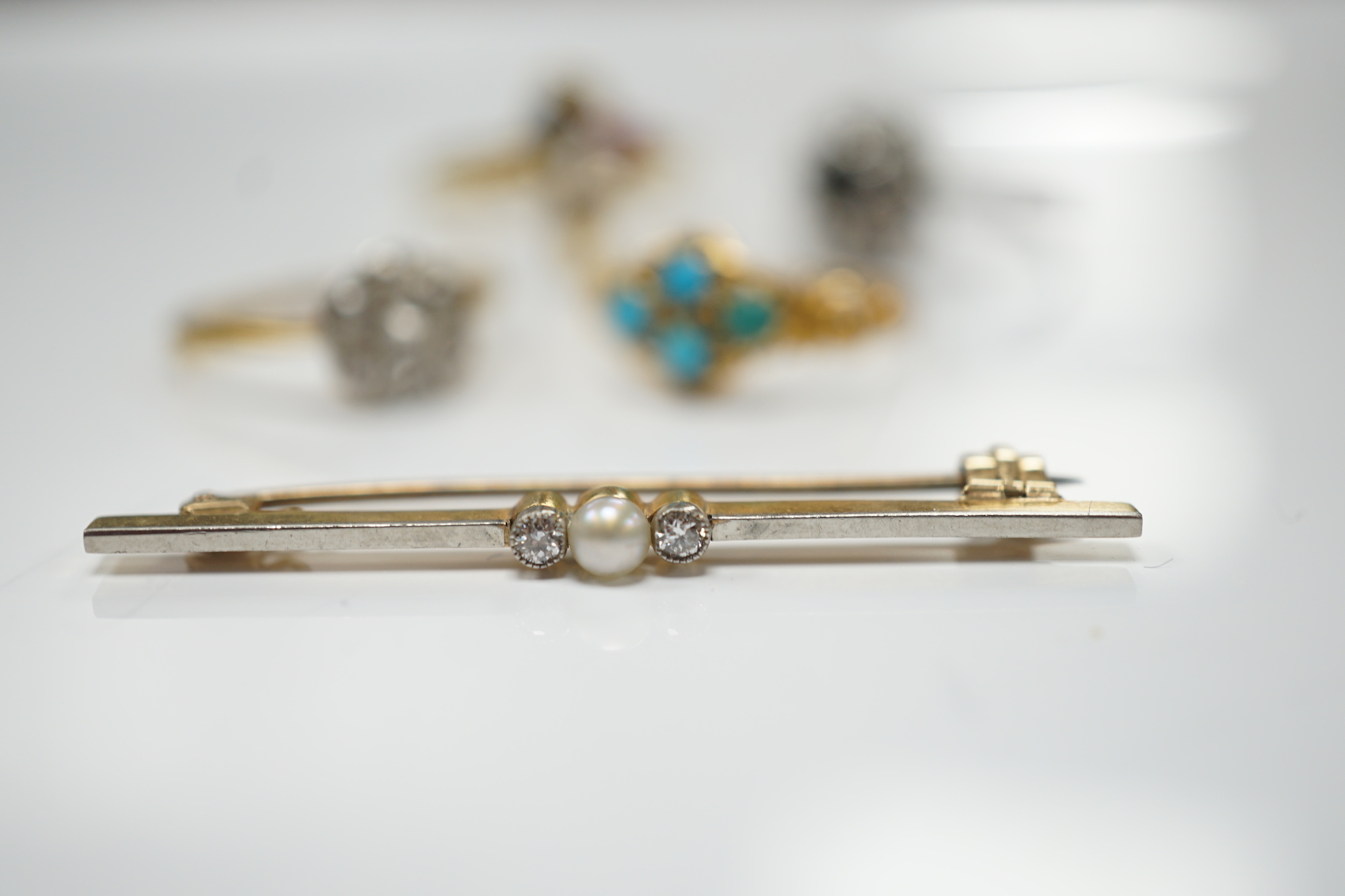 Three assorted 18ct and gem set rings, including 1920's diamond cluster, size K/L, one other early 20th century yellow metal and turquoise cluster set ring and a 15ct, diamond and seed pearl set three stone bar brooch.